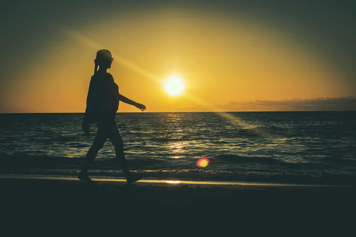 Silhouette einer Frau am Strand vor dem Sonnenuntergang